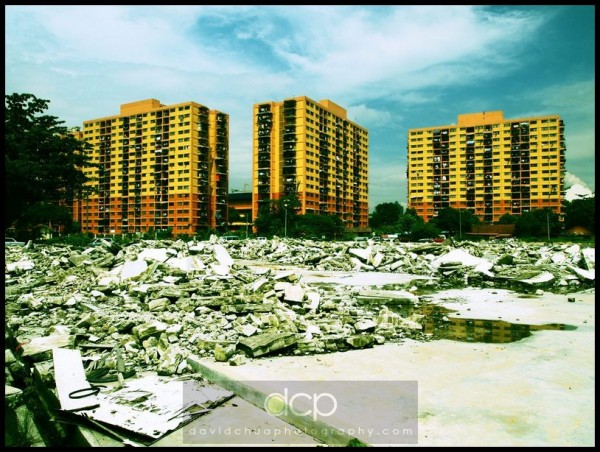 Uncleared mess from a torn-down building with apartment flats in the background